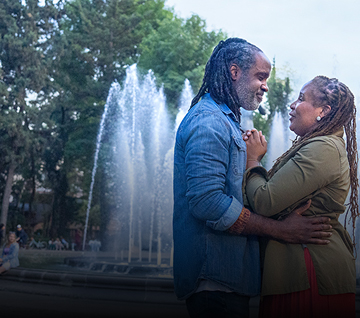 Man and woman embracing each other in front of a fountain