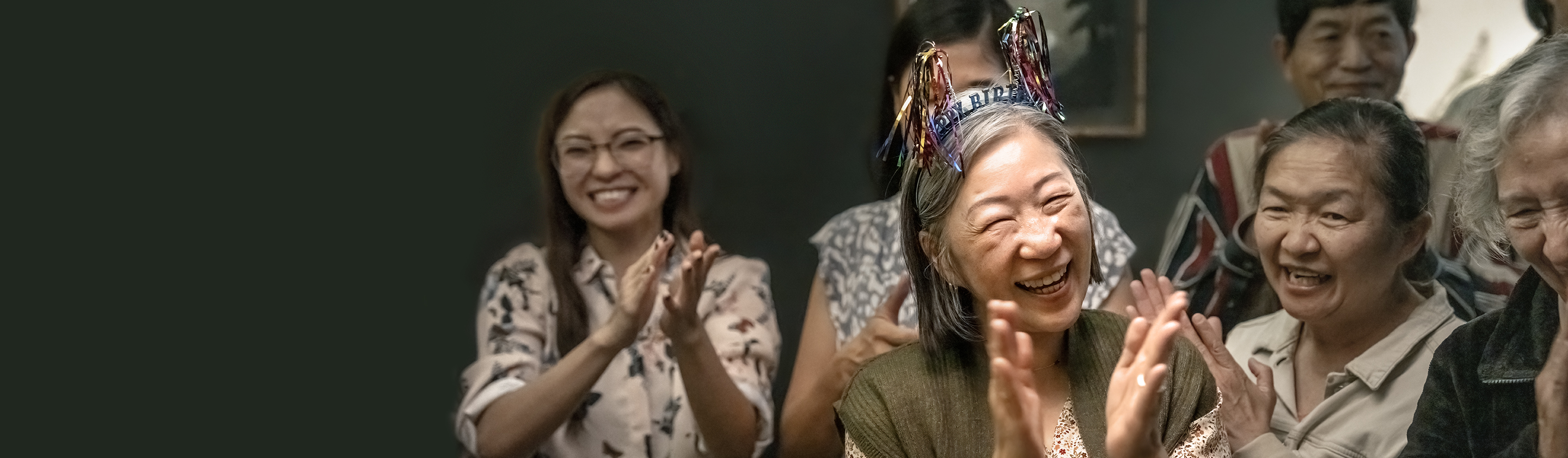 Elderly woman celebrating her birthday with people clapping around her