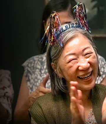 Elderly woman celebrating her birthday with people clapping around her
